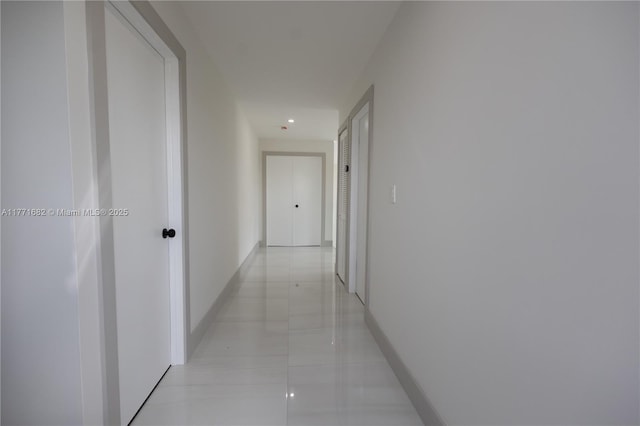 hall featuring baseboards and light tile patterned flooring