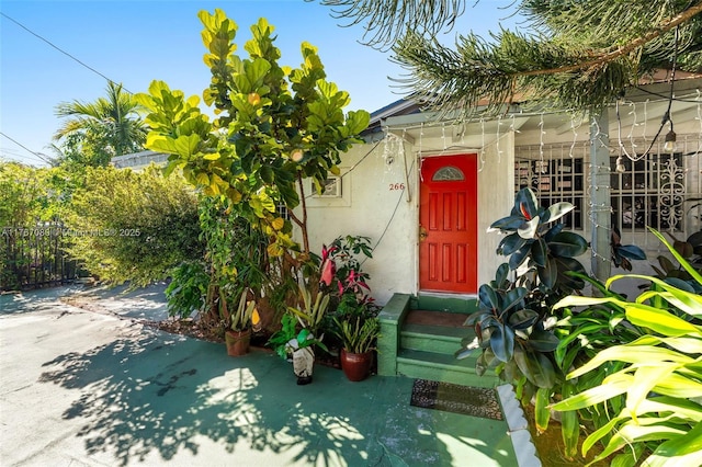 property entrance featuring stucco siding and fence