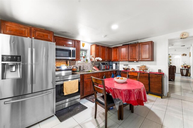 kitchen featuring backsplash, vaulted ceiling, stainless steel appliances, and light tile patterned floors