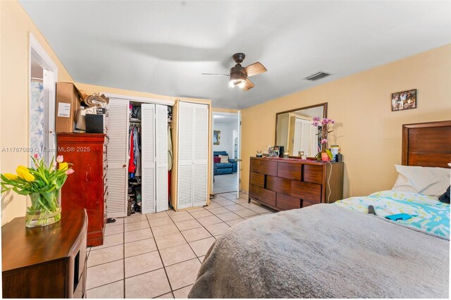 bedroom featuring a ceiling fan, light tile patterned flooring, multiple closets, and visible vents