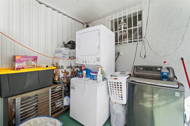 laundry room featuring a textured wall and stacked washer and dryer
