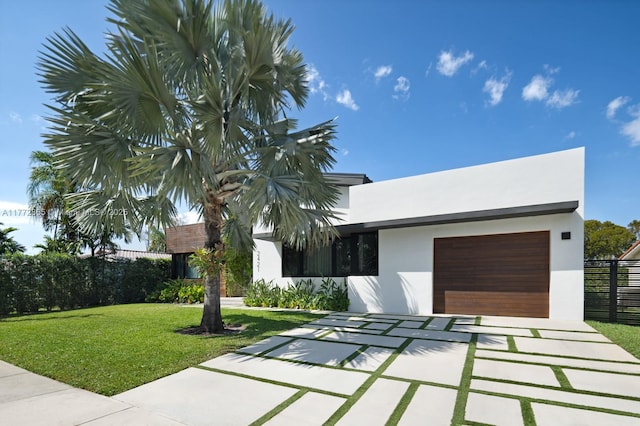 2421 NE 199th St, Miami, FL 33180 - view of front of house featuring driveway, a front yard, stucco siding, fence, and an attached garage