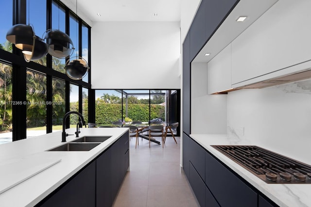 2421 NE 199th St, Miami, FL 33180 - kitchen featuring light tile patterned floors, black stovetop, decorative backsplash, a sink, and modern cabinets