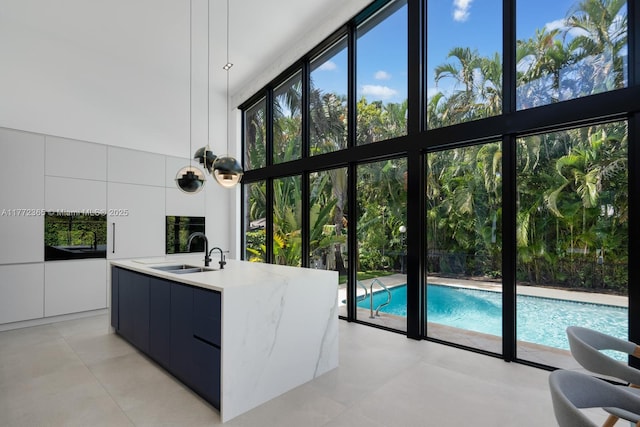 2421 NE 199th St, Miami, FL 33180 - kitchen with a wall of windows, modern cabinets, white cabinetry, a sink, and pendant lighting
