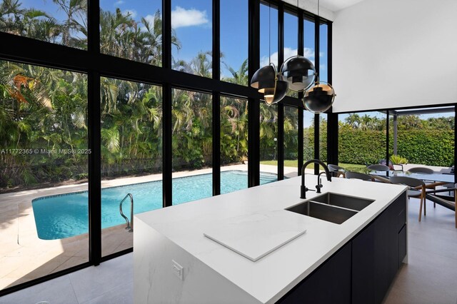 2421 NE 199th St, Miami, FL 33180 - kitchen with light countertops, a sink, modern cabinets, a center island with sink, and dark cabinets
