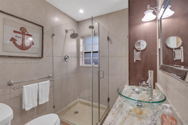 bathroom featuring toilet, a sink, and a stall shower