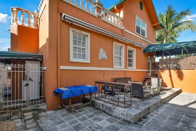 rear view of property featuring a gate, a patio, and stucco siding