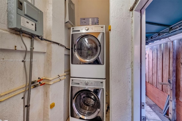 laundry room featuring a textured wall and stacked washer and clothes dryer