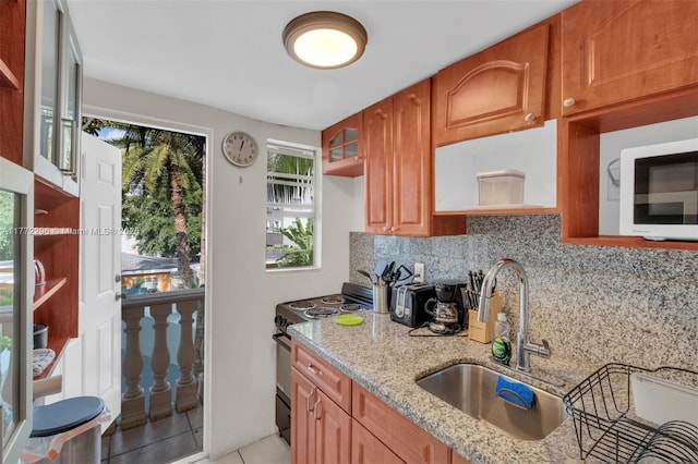 kitchen with backsplash, electric range oven, light stone counters, and a sink