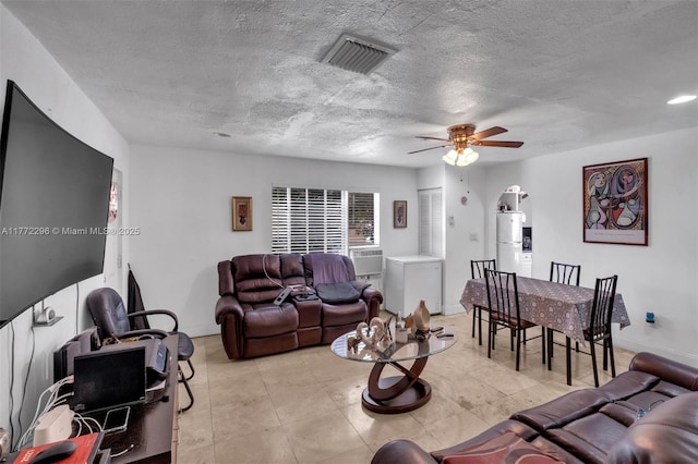 living room with a textured ceiling, visible vents, a ceiling fan, and baseboards