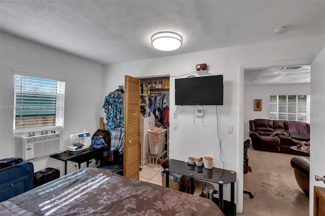 bedroom with tile patterned floors, cooling unit, and a closet