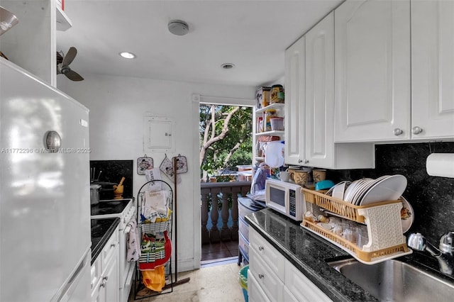 kitchen with tasteful backsplash, dark stone countertops, white appliances, ceiling fan, and white cabinetry