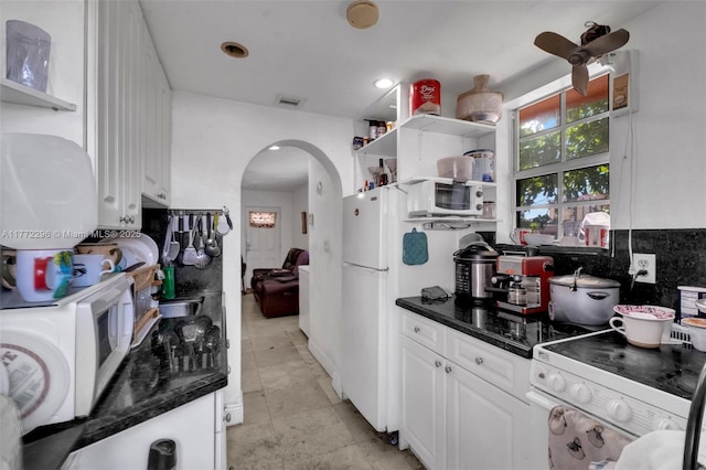 kitchen featuring open shelves, white appliances, arched walkways, and visible vents