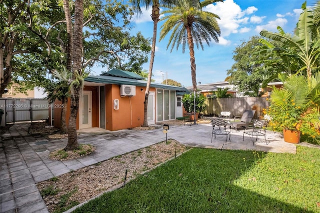 rear view of property featuring a wall mounted air conditioner, a lawn, roof mounted solar panels, fence, and a patio