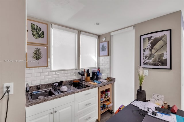 kitchen featuring decorative backsplash, a sink, and white cabinetry