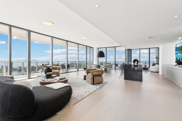 living area with floor to ceiling windows, a water view, light wood-style flooring, visible vents, and recessed lighting