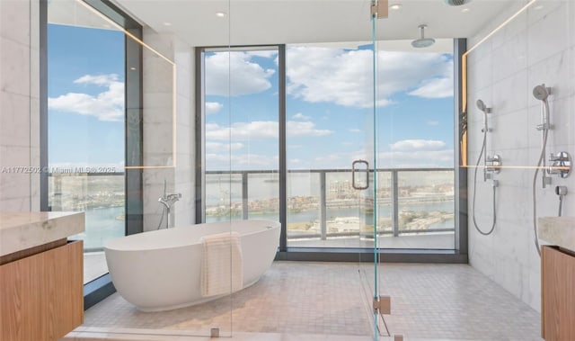 full bathroom featuring a wall of windows, a shower stall, vanity, and a freestanding bath