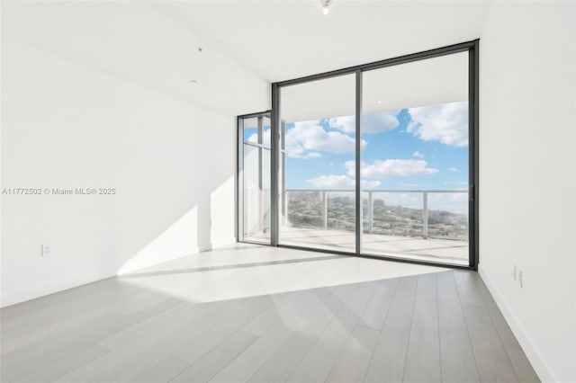 unfurnished room with wood finished floors and floor to ceiling windows