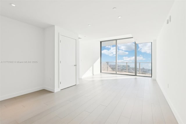 unfurnished room with baseboards, wood finished floors, and floor to ceiling windows