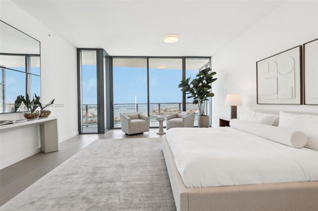 bedroom featuring baseboards, a wall of windows, and wood finished floors