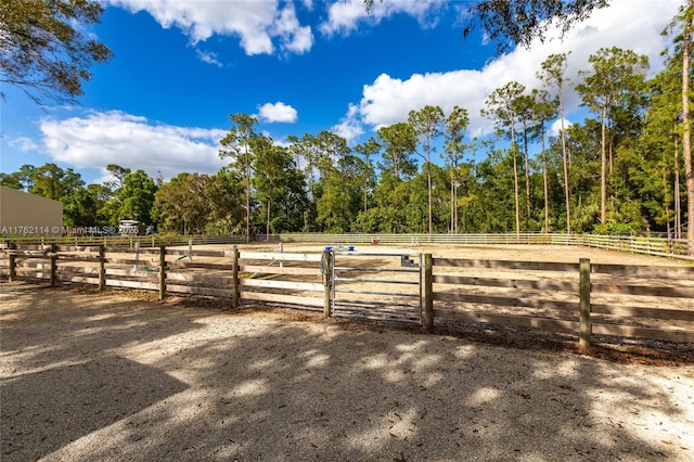 view of yard with an enclosed area, fence, and a rural view