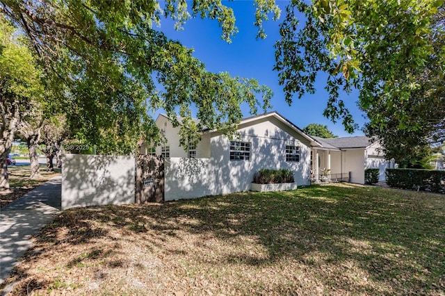 view of front of house featuring stucco siding, fence, and a front yard
