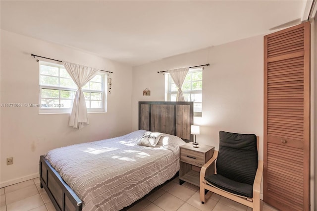 bedroom with baseboards, a closet, and light tile patterned floors