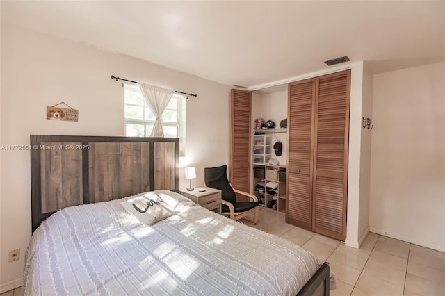 bedroom with a closet, baseboards, visible vents, and light tile patterned floors