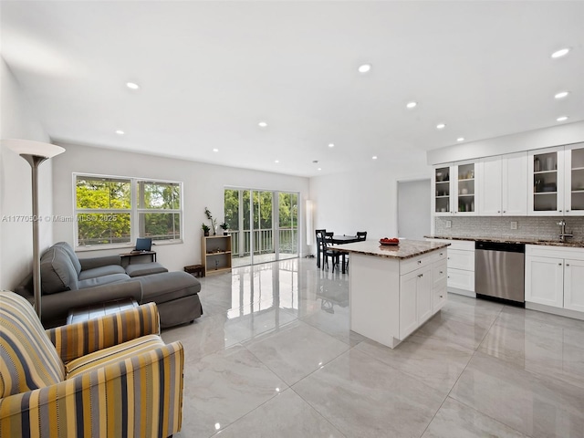 300 Diplomat Pkwy Unit 204, Hallandale Beach, FL 33009 - kitchen with a kitchen island, tasteful backsplash, glass insert cabinets, open floor plan, and stainless steel dishwasher