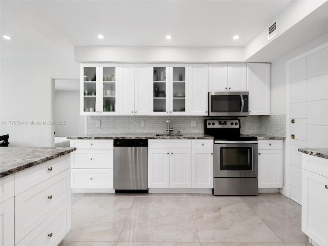 300 Diplomat Pkwy Unit 204, Hallandale Beach, FL 33009 - kitchen featuring dark stone countertops, decorative backsplash, a sink, visible vents, and appliances with stainless steel finishes