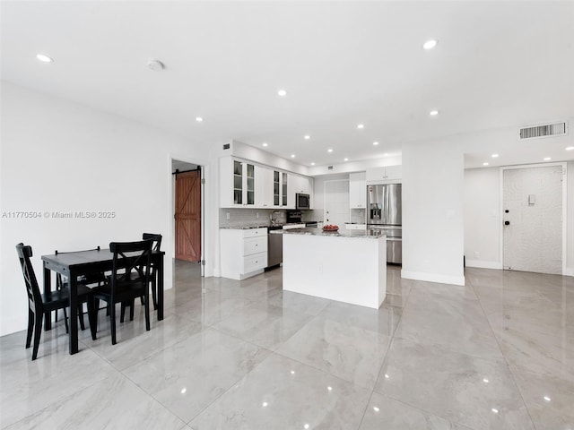 300 Diplomat Pkwy Unit 204, Hallandale Beach, FL 33009 - kitchen featuring visible vents, stainless steel appliances, a kitchen island, glass insert cabinets, and a barn door