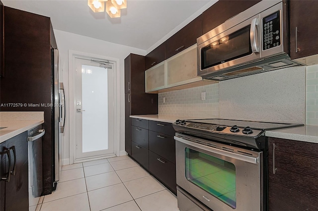 1030 9th St Unit 203, Miami Beach, FL 33139 - kitchen with stainless steel appliances, light countertops, decorative backsplash, light tile patterned floors, and dark brown cabinets