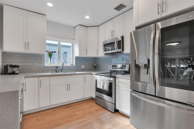 kitchen with a sink, visible vents, white cabinetry, and stainless steel appliances