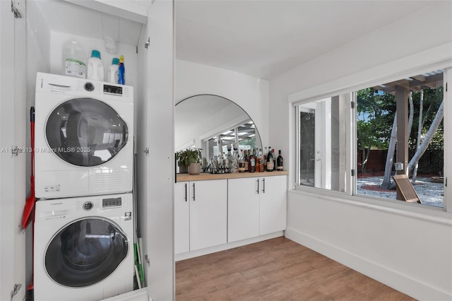 laundry room with light wood-style flooring, laundry area, and stacked washer / drying machine