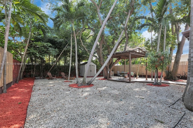view of yard with an outbuilding, a shed, a fenced backyard, and a patio area