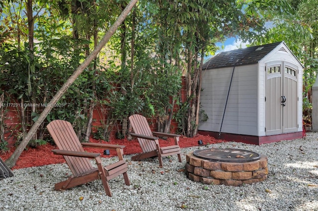 exterior space with a fire pit, an outbuilding, and a storage unit