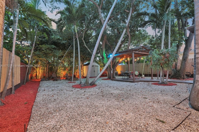 view of yard with a storage shed, a patio area, a fenced backyard, and an outdoor structure