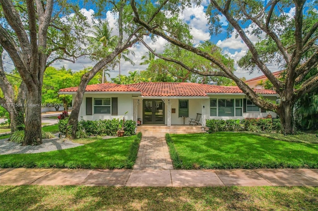 view of front of house featuring french doors, a tile roof, a front yard, and stucco siding