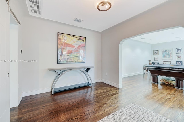 interior space with baseboards, visible vents, wood finished floors, and arched walkways