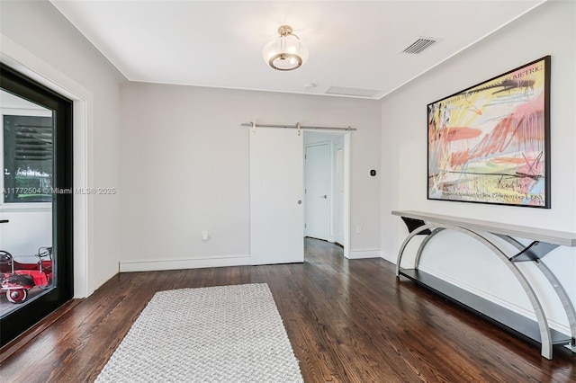 interior space featuring wood finished floors, baseboards, a barn door, and visible vents