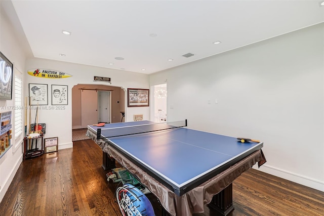 recreation room featuring baseboards, visible vents, wood finished floors, and arched walkways