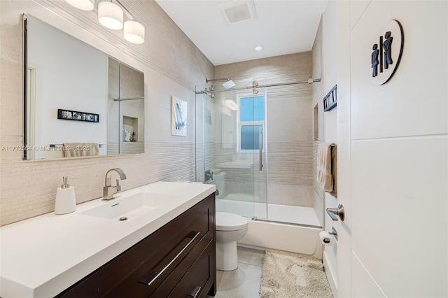 bathroom featuring vanity, tile walls, toilet, backsplash, and combined bath / shower with glass door