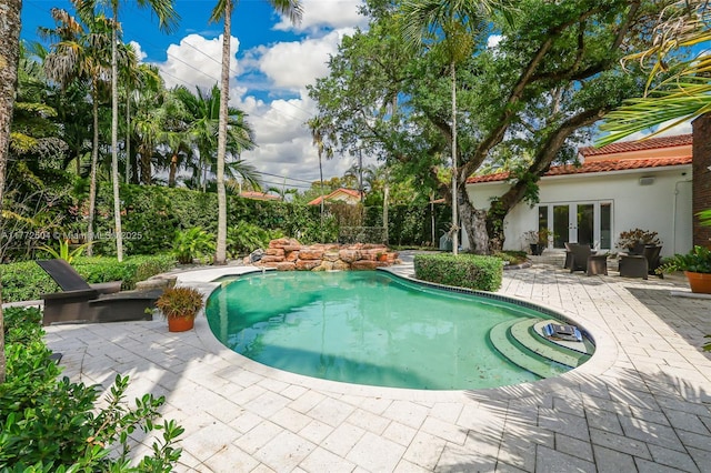 view of swimming pool featuring a patio, a fenced in pool, and french doors