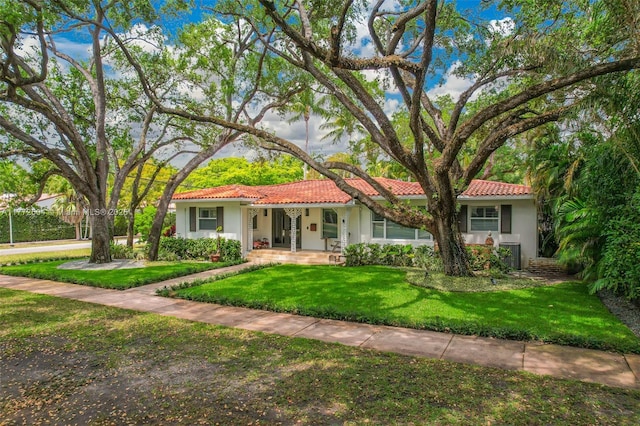 view of front facade with stucco siding, a tile roof, and a front lawn