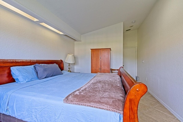 bedroom with baseboards, a textured wall, visible vents, and vaulted ceiling
