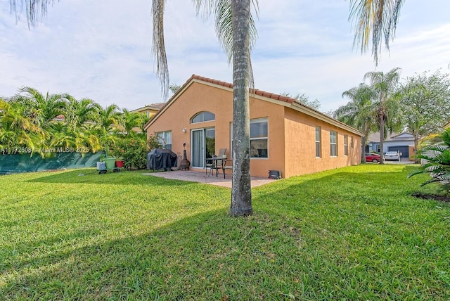 back of property with stucco siding, a patio, and a yard