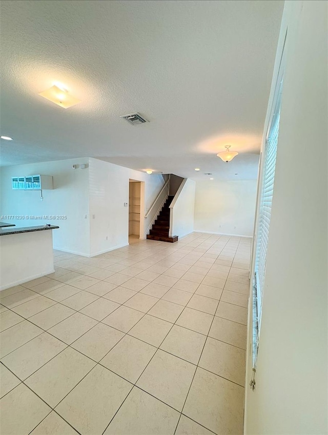 3210 NW 126th Ave Unit 3210, Sunrise, FL 33323 - unfurnished living room with stairs, light tile patterned flooring, baseboards, and a textured ceiling