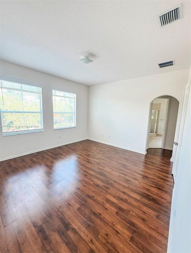 3210 NW 126th Ave Unit 3210, Sunrise, FL 33323 - unfurnished room featuring arched walkways, dark wood-style flooring, baseboards, and a textured ceiling