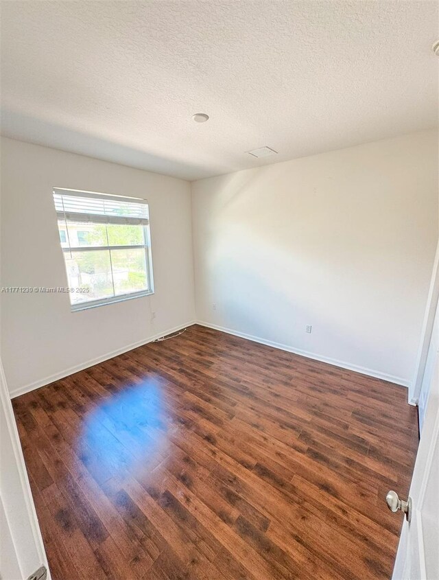 3210 NW 126th Ave Unit 3210, Sunrise, FL 33323 - spare room featuring dark wood-type flooring, a textured ceiling, and baseboards