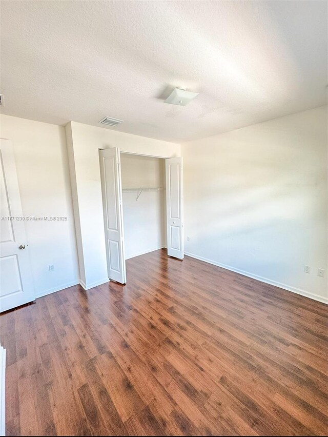 3210 NW 126th Ave Unit 3210, Sunrise, FL 33323 - unfurnished bedroom featuring dark wood finished floors, a closet, a textured ceiling, and baseboards